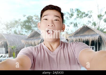 Asian man making selfie using the camera phone with cottage background Stock Photo