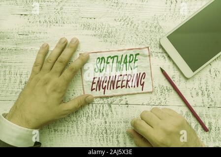 Conceptual hand writing showing Software Engineering. Concept meaning apply engineering to the development of software Hand hold note paper near writi Stock Photo