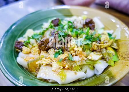 A bowl of biang biang mian noodles, a famous dish from the city of Xi'an, at the Muslim street night market in Xian, in the Shaanxi province of China Stock Photo