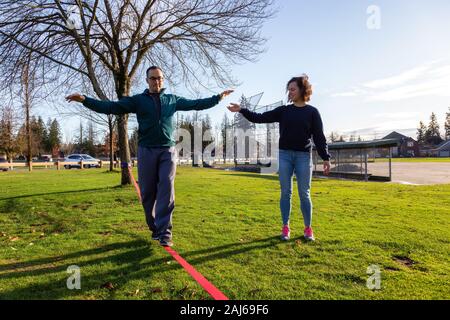 Couple walking on a Slackline in the Park Stock Photo