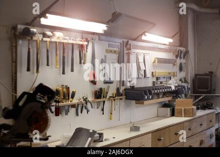 Image of workshop with work place and work tools hanging on the wall Stock Photo