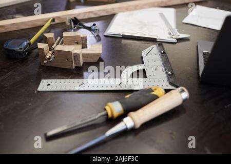 Close-up of table with wooden details and work tools in the workshop Stock Photo