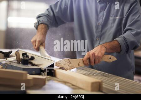 Close-up of carpenter standing near the lathe holding wooden details and cutting them in the plant Stock Photo