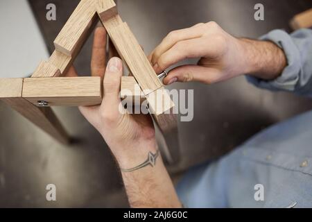 Close-up of man making figure or furniture from wood he standing and tightening the screw Stock Photo
