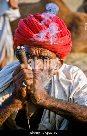 Farmer smoking marihuana during Pushkar Camel Fair, one of the largest camel-markets in Asia Stock Photo