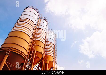 Cement silos of Cement batching plant factory against evening warm clear sky with space for text Stock Photo