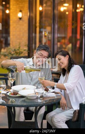 Mature Chinese couple drinking wine at restaurant Stock Photo