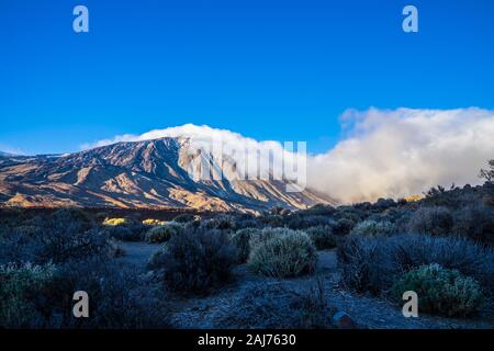 Spain, Tenerife, Beautiful blue sky over world famous mountain volcano teide with fog clouds and plants in caldera desert nature landscape Stock Photo