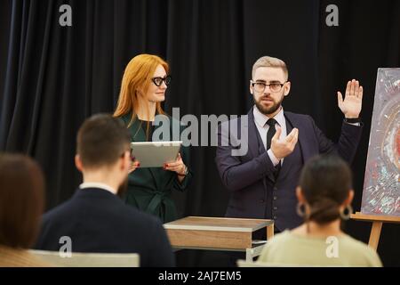 Businesswoman with tablet pc and businessman presenting the modern art to people during conference Stock Photo