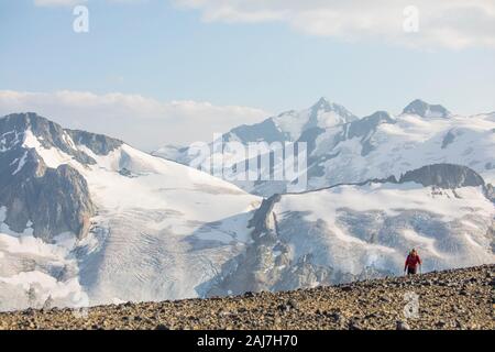 Small man emerges over ridge crest in front of glacier Stock Photo