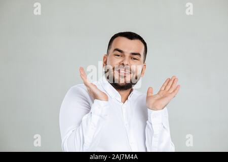 Portrait of young surprised handsome bearded man with shocked facial expression on gray background Stock Photo