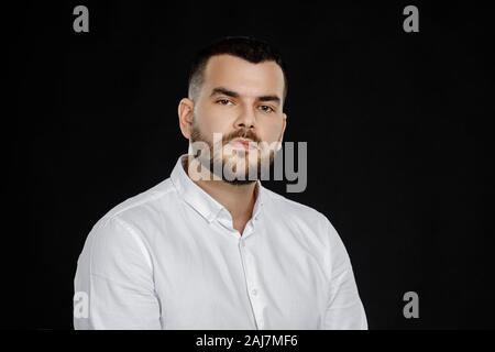 calm handsome bearded man poses in studio on black background Stock Photo