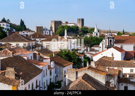 View across the rooftops and ancient streets and houses of Portuguese village of Obidos looking towards Obidos castle. Photograph: Tony Taylor Stock Photo