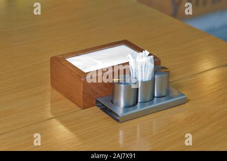 White napkins in a metal napkin holder, spices salt and pepper on a wooden table, panoramic view . metal napkin holder isolated on wooden background Stock Photo