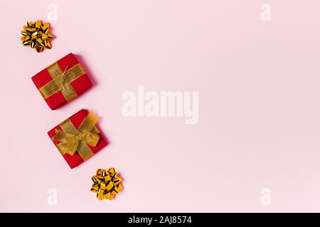 Holiday card. Two red gift boxes with golden ribbon on pink background. Place for text. Stock Photo