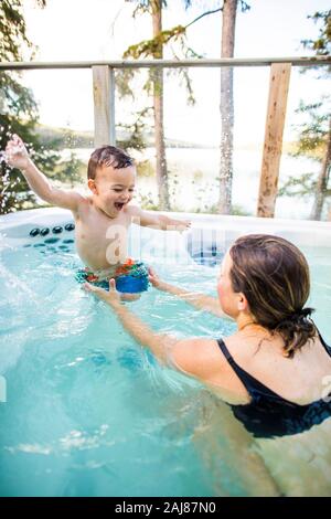 Young boy laughing and smiling with swimming ans splashing in pool. Stock Photo