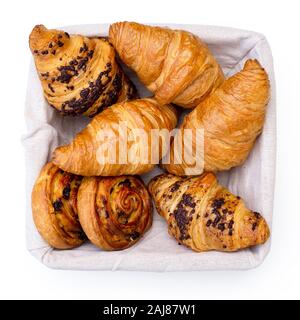 Plain and chocholate croissants and rasin danish pastry swirls in linen basket isolated on white from above. Stock Photo