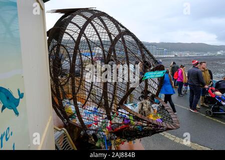 Filup The Fish, created by metal artist Robert Floyd, for plastic waste bottle collection on the promenade at Westward Ho! North Devon, UK Stock Photo