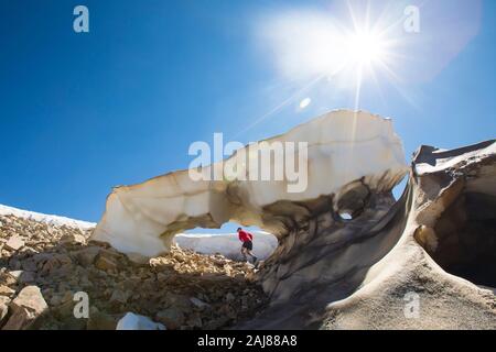 Side view of man trail running through melting glaciers. Stock Photo