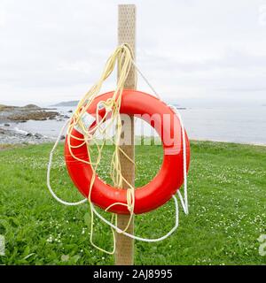 Orange life buoy at Witless Bay in Newfoundland and Labrador, Canada. The safety device is designed for use by people in the water. Stock Photo