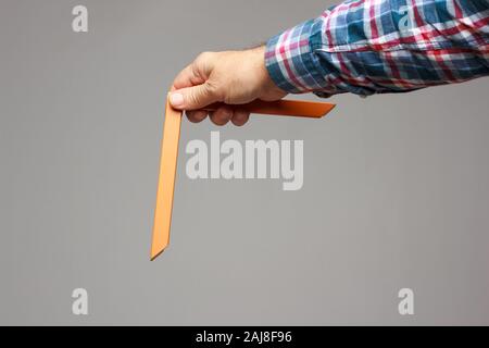 Object in the form of a geometric part with an angle of 90 degrees in the expert hand of a professional; object to take measurements and calculate rig Stock Photo