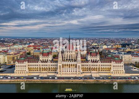 Budapest, Hungary - Aerial drone view of the beautiful Hungarian Parliament building at sunset with sightseeing floating bus on River Danube and tradi Stock Photo