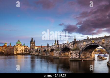 Prague, Czech Republic - Beautiful purple sunset and sky at the world famous Charles Bridge (Karluv most) and St. Francis Of Assisi Church on a winter
