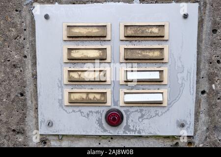 Old and weathered metal doorbell panel  with unreadable names with a red light switch on a frosty morning in winter. Seen in January in Bavaria, Germa Stock Photo