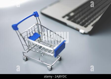 close up of a tiny cart and a laptop isolated - shopping cart and e-commerce Stock Photo