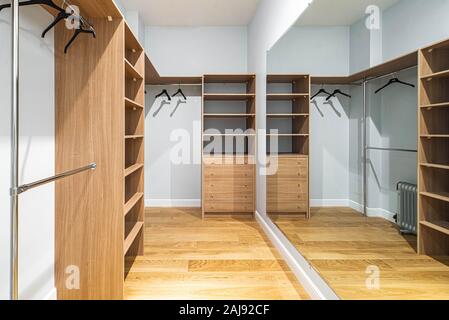 An empty dressing room with wooden shelves, drawers, and hangers. Reflection in the mirror. Stock Photo