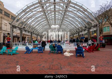 Reston, VA, USA — January 2, 2020. Wide angle shot of people watching ice skaters at an outdoor rink in Reston Town Center, Virginia. Stock Photo