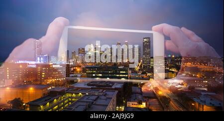Double exposure of hands holding a phone taking a photo of downtown Los Angeles at night Stock Photo