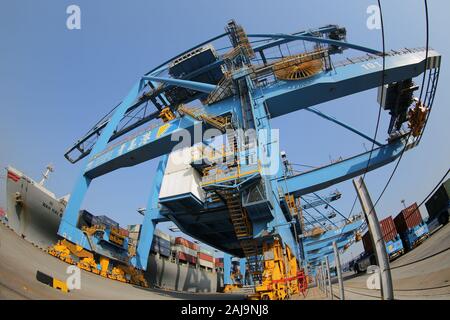 Containers are lifted by cranes from unmanned trucks to be loaded onto a ship on a quay at the Port of Qingdao in Qingdao City, east China's Shandong Stock Photo