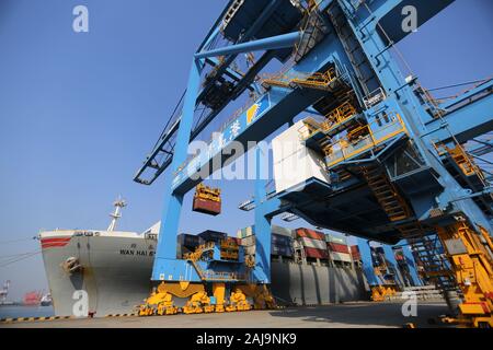 Containers are lifted by cranes from unmanned trucks to be loaded onto a ship on a quay at the Port of Qingdao in Qingdao City, east China's Shandong Stock Photo