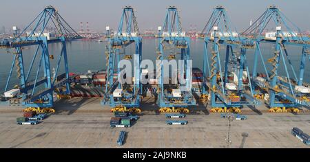 Containers are lifted by cranes from unmanned trucks to be loaded onto a ship on a quay at the Port of Qingdao in Qingdao City, east China's Shandong Stock Photo