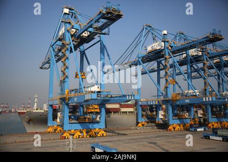 Containers are lifted by cranes from unmanned trucks to be loaded onto a ship on a quay at the Port of Qingdao in Qingdao City, east China's Shandong Stock Photo