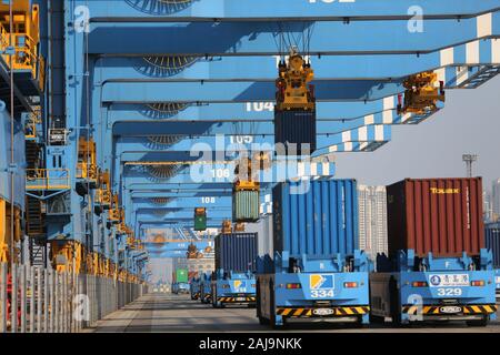 Containers are lifted by cranes from unmanned trucks to be loaded onto a ship on a quay at the Port of Qingdao in Qingdao City, east China's Shandong Stock Photo