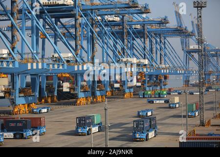 Containers are lifted by cranes from unmanned trucks to be loaded onto a ship on a quay at the Port of Qingdao in Qingdao City, east China's Shandong Stock Photo