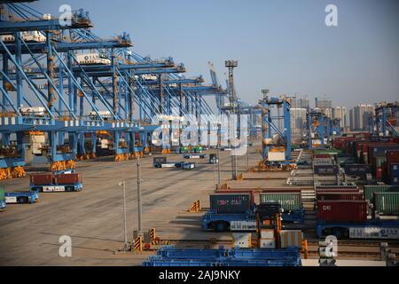 Containers are lifted by cranes from unmanned trucks to be loaded onto a ship on a quay at the Port of Qingdao in Qingdao City, east China's Shandong Stock Photo