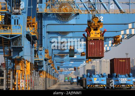 Containers are lifted by cranes from unmanned trucks to be loaded onto a ship on a quay at the Port of Qingdao in Qingdao City, east China's Shandong Stock Photo