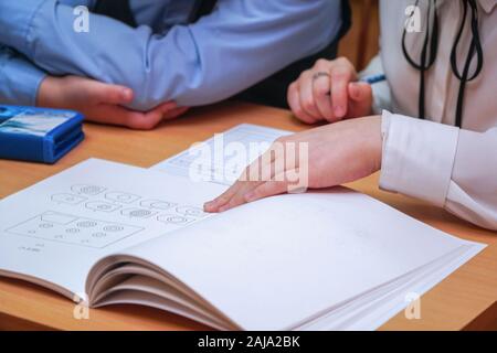The teacher points a finger at the shapes in the geometry textbook. Selective focus Stock Photo