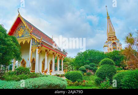 Relax in amazing garden of Wat Chalong temple with lush greenery, topiary plants, colorful flower beds and a view on stunning shrines and tall chedi,