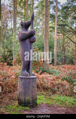 Carved wooden sculpture carving of a bear stood to attention with a spear by trail in woodland at Sandringham in Norfolk Stock Photo