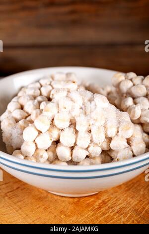 Frozen chickpeas in bowl on wooden background. Stock Photo