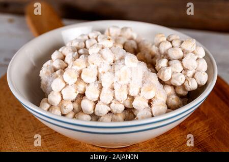 Frozen chickpeas in bowl on wooden background. Stock Photo