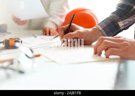 A team of architects develop a drawing for construction projects. Engineers create a sketch at the workplace. Construction concept. Stock Photo