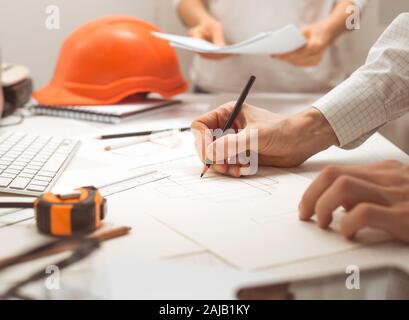A team of architects develop a drawing for construction projects. Engineers create a sketch at the workplace. Construction concept. Stock Photo