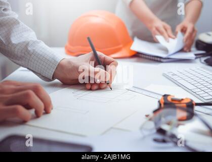 A team of architects develop a drawing for construction projects. Engineers create a sketch at the workplace. Construction concept. Stock Photo