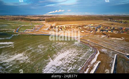 Winter countryside. Fields with winter crops and plowed field. Fields covered with snow. Aerial view. Snow covered farmland and trees during winter. M Stock Photo