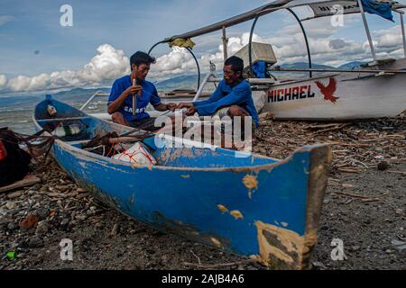 Palu City, Indonesia. 03rd Jan, 2020. Two fishermen working on a torn fishing net.High waves in the waters of Palu Bay forced Hundreds of fishermen in the village of Lere to anchor their boats. According to the Palu Meteorology, Climatology and Geophysics Agency (BMKG) the waves reached two meters to three meters, considered quite dangerous for fishermen. Credit: SOPA Images Limited/Alamy Live News Stock Photo